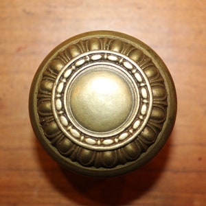May include: A gold-toned door knob with a decorative, ornate design.