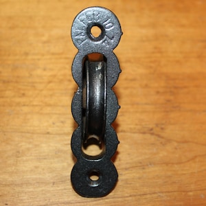 May include: Black cast iron pulley with a single wheel and four mounting holes. The pulley has the text "PAT'D JULY 10, '95" on the top.