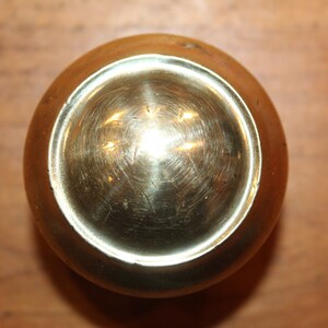 May include: A brass door knob with a round, polished surface.