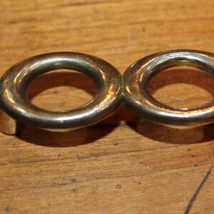 May include: A gold-toned metal ring holder with two circular openings. The holder is designed to hold two rings.