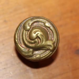 May include: A brass cabinet knob with a decorative swirl design.