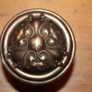 May include: A vintage-style door knob with an ornate, detailed design. The knob is made of metal and has a dark, aged finish.