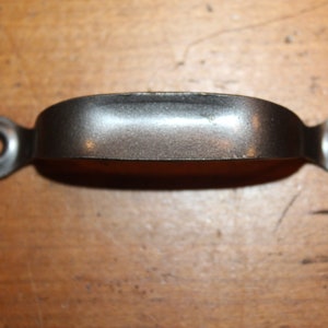 May include: A silver-toned metal drawer pull with rounded edges and two small circular holes on each end.