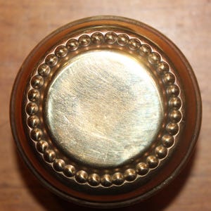 May include: A round, brass door knob with a beaded edge.