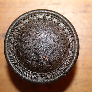 May include: A black metal door knob with a decorative ring around the edge.