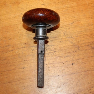 May include: A vintage door knob with a dark brown wooden handle and a metal shaft.