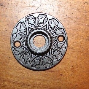 May include: A black metal door knob rosette with a decorative floral design.