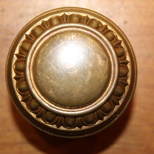 May include: A gold-toned door knob with a decorative, beaded rim.