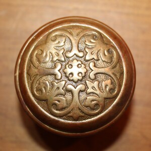 May include: A brass door knob with an ornate floral design.