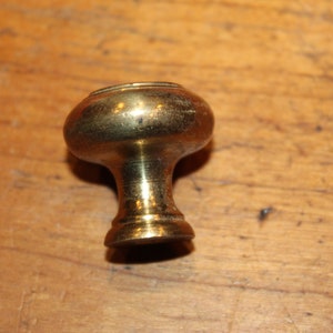 May include: A brass cabinet knob with a round top and a short, cylindrical base.