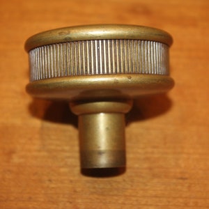 May include: A brass filter with a ribbed top and a threaded bottom. The filter is designed to remove impurities from liquids.