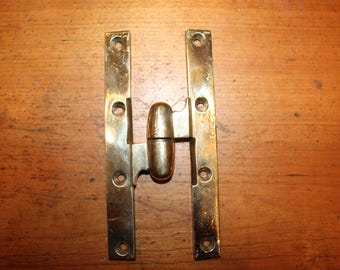 May include: A brass hinge with a barrel-shaped center and two rectangular leaves, each with multiple screw holes. The hinge is a warm gold color and appears to be vintage or antique.