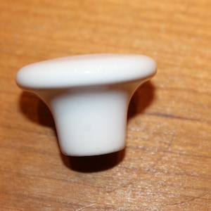 May include: White ceramic cabinet knob with a rounded top and a slightly flared base.
