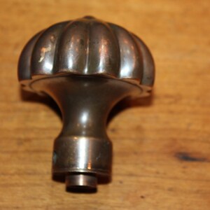 May include: A vintage brass door knob with a fluted, rounded top. The knob has a smooth, polished finish.