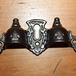 May include: Black cast iron door or window hardware with a keyhole and two decorative finials.