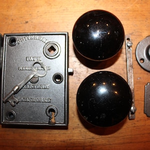 May include: Antique door hardware set with black porcelain knobs, a keyhole cover, a strike plate, and a key with the text "DAHL  NEW YORK  RANDOLPH  LOCK WORKS".