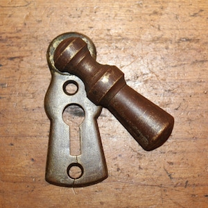 May include: Antique brass door knob with a keyhole and a round handle. The knob is worn and has a patina finish.