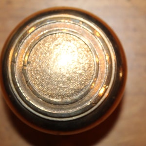 May include: A gold-toned door knob with a circular design and concentric rings.