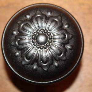 May include: A black metal door knob with a decorative floral design.