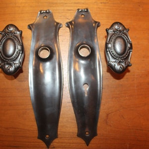 May include: Two antique silver door plates with a keyhole and a decorative design. Two matching silver door knobs with a decorative design.