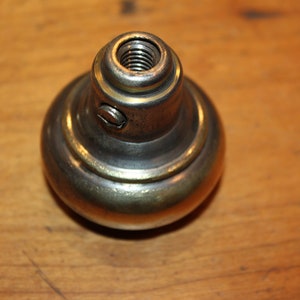 K&ouml;nnte beinhalten: Ein Messing-T&uuml;rknopf mit einem Gewinde oben und einem goldenen Band in der Mitte.
