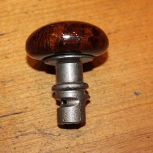 May include: A dark brown wooden knob with a silver metal base and a threaded shaft. The knob is round and has a smooth finish.