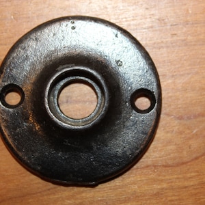 May include: Black metal door knob backplate with two holes for screws.