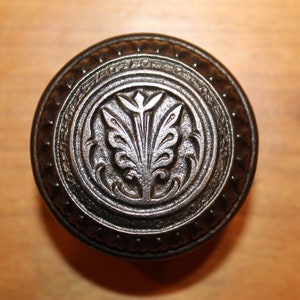 May include: A black metal door knob with a decorative floral design.
