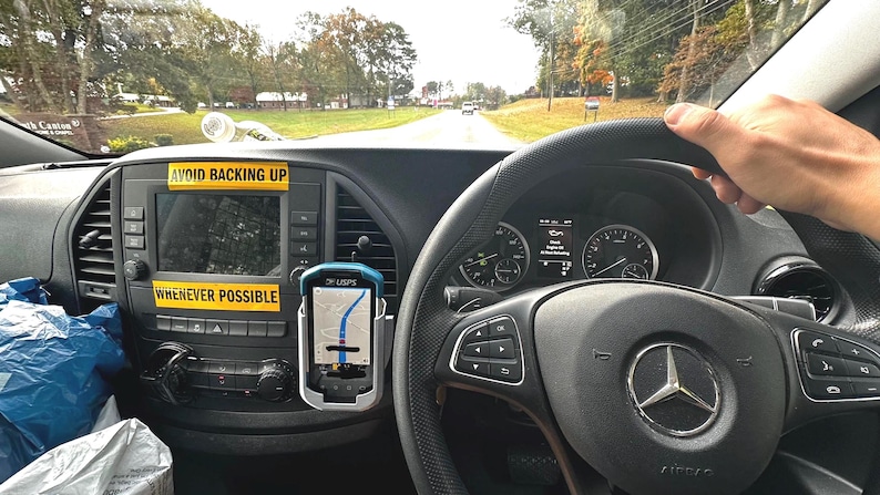 Puede incluir: Vista interior del salpicadero de un veh&iacute;culo, con un volante con el logotipo de Mercedes-Benz. Un dispositivo GPS muestra un mapa. Pegatinas amarillas con las frases "AVOID BACKING UP" y "WHENEVER POSSIBLE".