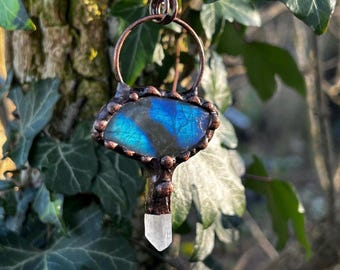 May include: A copper pendant with a blue labradorite stone and a clear quartz crystal. The pendant is hanging from a copper chain.
