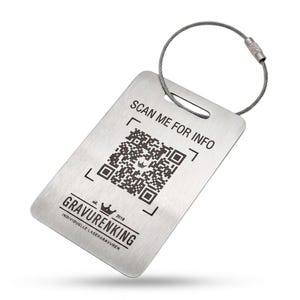May include: A rectangular brushed metal luggage tag with rounded corners, featuring a laser-engraved QR code, the text SCAN ME FOR INFO, and the logo GRAVURENKING with a crown icon. A flexible silver-toned wire cable loop is attached to the top.