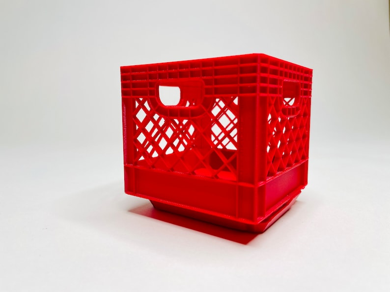 Puede incluir: Una caja de leche de pl&aacute;stico rojo brillante con forma rectangular y dise&ntilde;o de celos&iacute;a. La caja tiene dos aberturas para asas en los lados. Este contenedor de almacenamiento es adecuado para diversos usos.