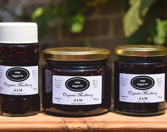 May include: Three glass jars of organic mulberry jam, labelled "Food Shack 777 Organic Mulberry Jam". The jars are different sizes, with the smallest jar containing 150 grams, the middle jar containing 300 grams, and the largest jar containing 150 grams.