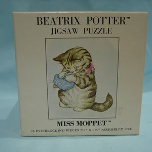 May include: A Beatrix Potter jigsaw puzzle featuring Miss Moppet, a tabby cat holding a blue and white mouse in her paws. The puzzle has 36 interlocking pieces and measures 7 1/2 inches by 7 1/2 inches when assembled.