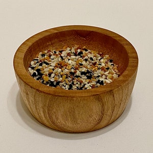 May include: A wooden bowl filled with a mixture of sesame seeds, poppy seeds, and black sesame seeds.