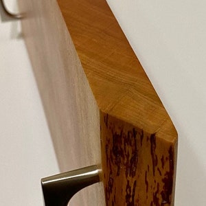 Op de afbeelding: Een houten dienblad met twee metalen handvatten. Het dienblad heeft een natuurlijke houten afwerking met een roodbruine tint. De handvatten zijn zilverkleurig en hebben een eenvoudig, modern ontwerp.