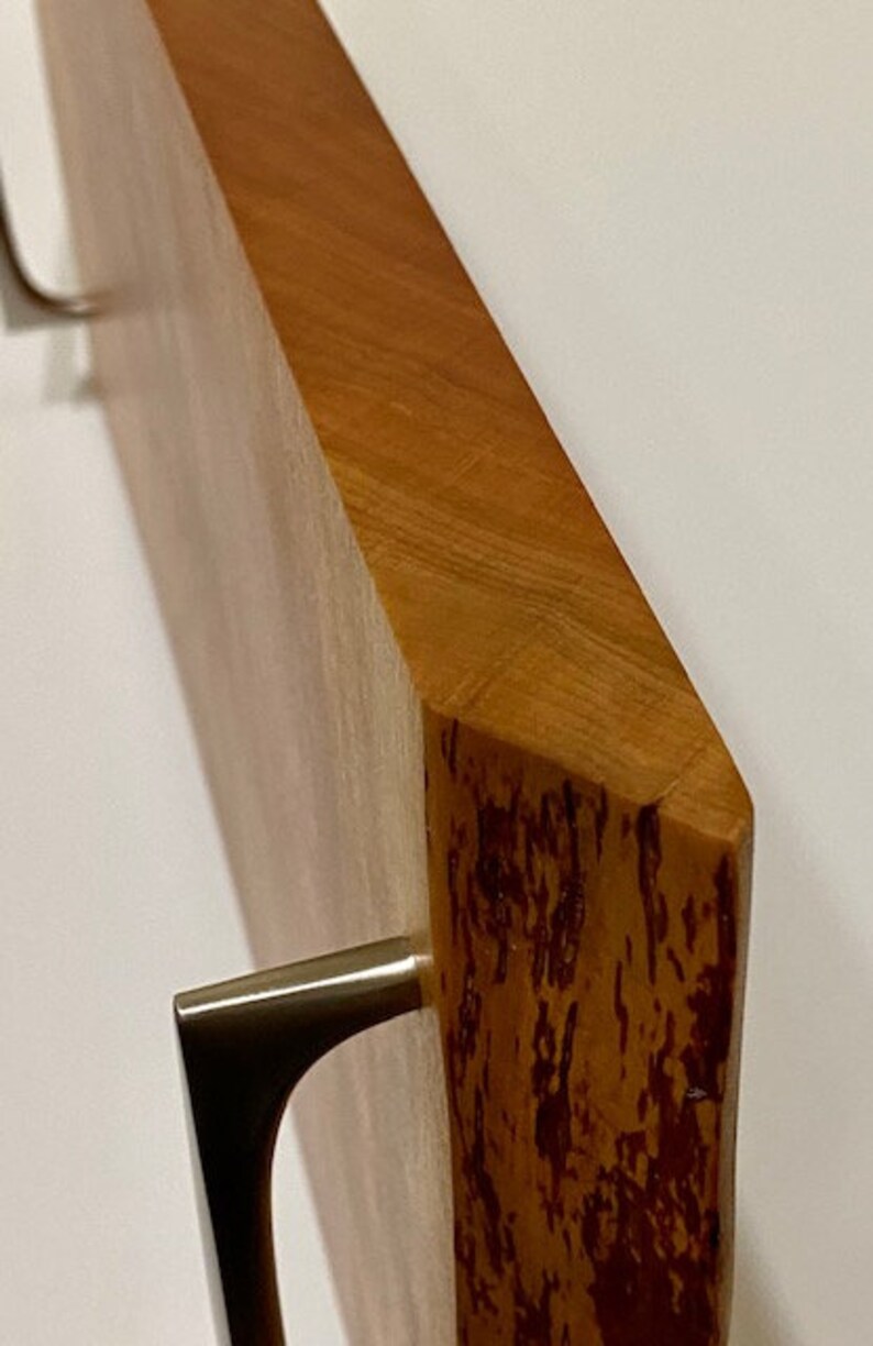 Op de afbeelding: Een houten dienblad met twee metalen handvatten. Het dienblad heeft een natuurlijke houten afwerking met een roodbruine tint. De handvatten zijn zilverkleurig en hebben een eenvoudig, modern ontwerp.