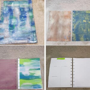 May include: A collection of open notebooks and journal pages. The covers feature abstract painted designs in shades of blue, green, brown, and purple. One notebook is open to blank lined pages.