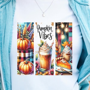 以下が含まれることがあります： 「Pumpkin Vibes」の文字が入った水彩デザインの白いTシャツ。デザインにはカボチャ、ラテ、パンプキンパイが含まれています。「Digital Download Only」の文字が画像の下部にあります。