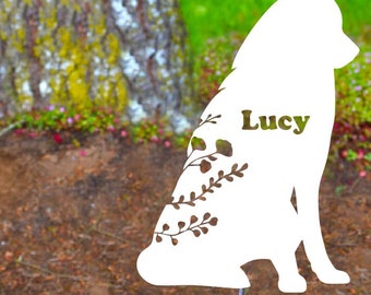 May include: White metal silhouette of a dog sitting with a floral design and the name "Lucy" cut out. The silhouette is on a metal stake.