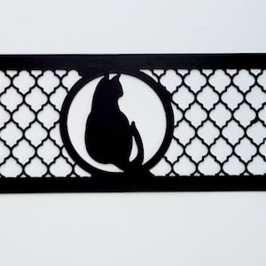Può includere: Decorazione da parete in metallo nero con un motivo geometrico e una silhouette di un gatto in un cerchio.