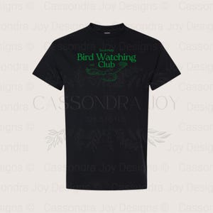 Puede incluir: Una camiseta negra de manga corta con texto verde que dice South Philly Bird Watching Club, con los a&ntilde;os 1998 y 2023 a ambos lados de un dibujo lineal de un p&aacute;jaro en vuelo, centrado en la zona del pecho de la prenda.