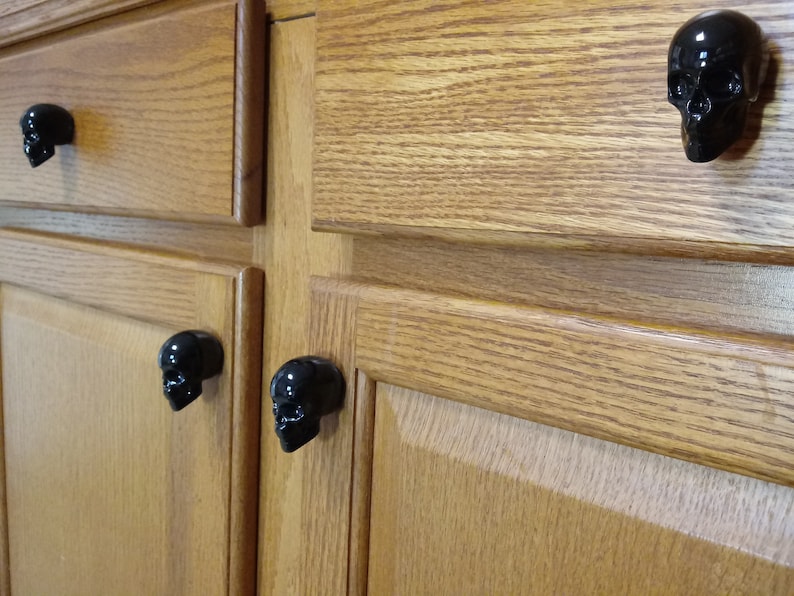 May include: Close-up of wooden cabinet doors with black skull-shaped drawer pulls.