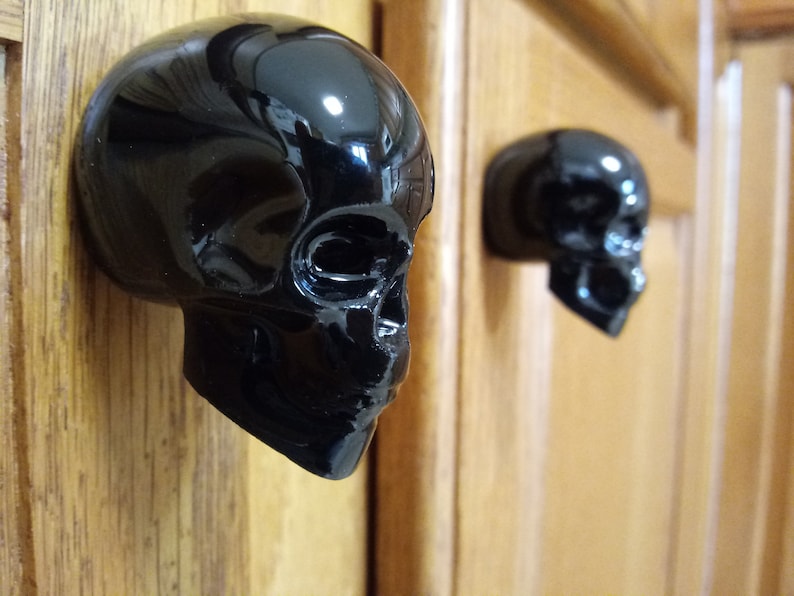 May include: Two black ceramic skull door knobs. The skulls are shiny and have a detailed design.