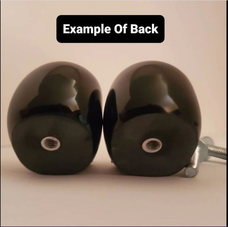 May include: Two black, round, smooth, wooden knobs with a threaded hole in the center. The knobs are attached to a metal screw.