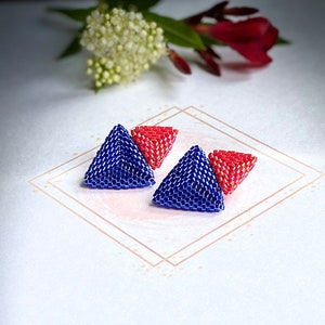 May include: A pair of blue and red triangle-shaped earrings made of beads. The earrings are layered, with a smaller red triangle on top of a larger blue triangle.