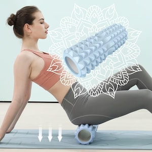 May include: A light blue foam roller with a textured, grid-like surface featuring raised bumps. The cylindrical exercise tool has a hollow center and is designed for muscle massage. The surface pattern consists of repeating geometric shapes.