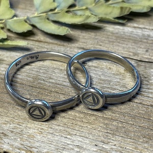 May include: Two silver rings with a triangle symbol on each. The rings are marked "925" and "DWg".