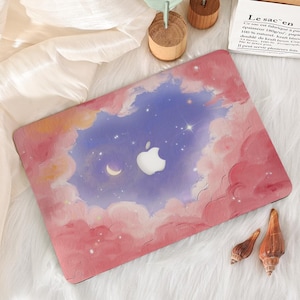 May include: A laptop case featuring a dreamy sky design with pink clouds, a blue sky, stars, and a crescent moon. The Apple logo is centered. The case is on a white, fluffy surface.