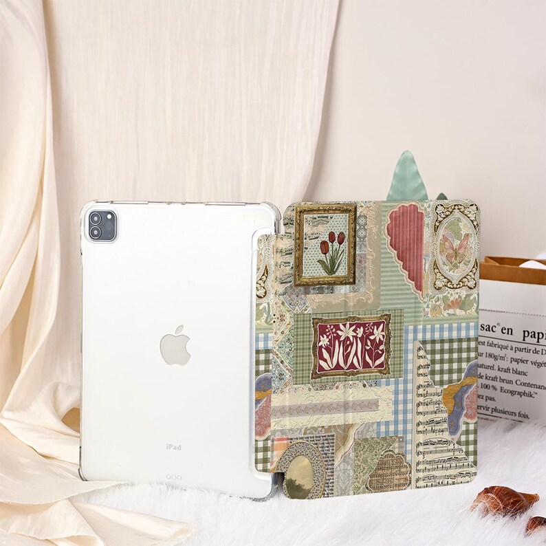 May include: A clear iPad case with a decorative cover featuring a collage of vintage-style images, including framed floral art, butterflies, and musical notes. The case is designed to protect the iPad while adding a touch of artistic flair.